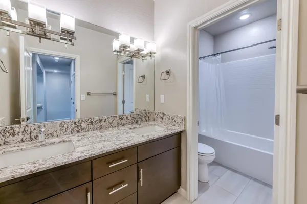 a bathroom with a granite countertop sink a toilet and a bathtub