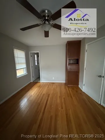 a view of an empty room with window and ceiling fan