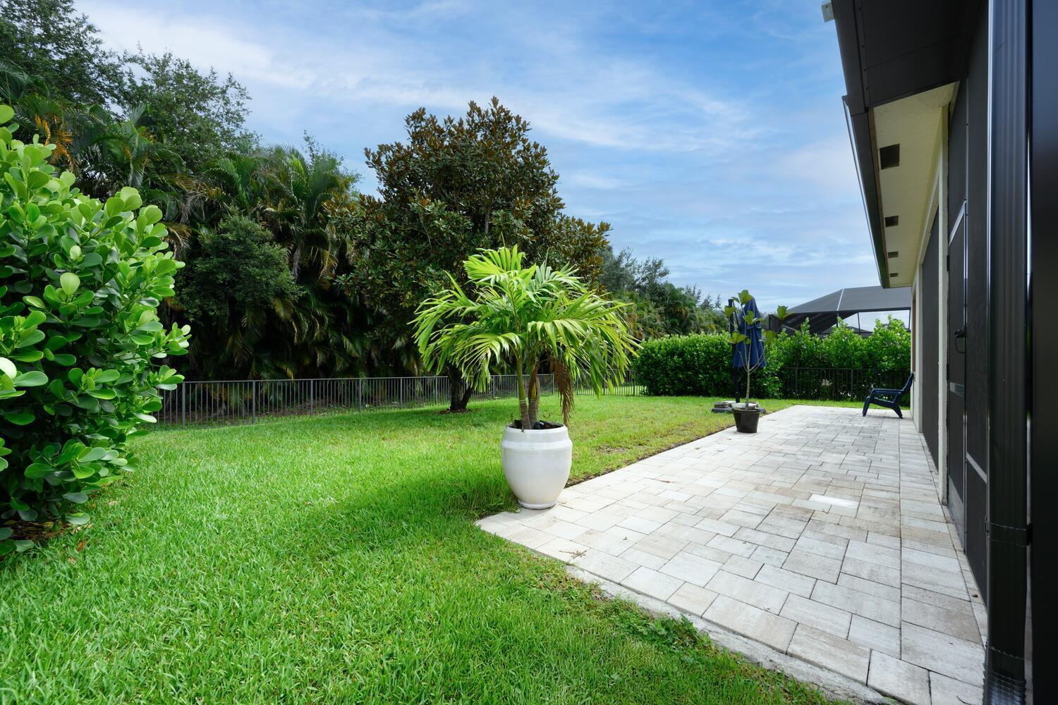 8024 Southwest Marin Drive Stuart, FL 34997 - Photo 21 of 26 a view of a backyard with potted plants and a palm tree