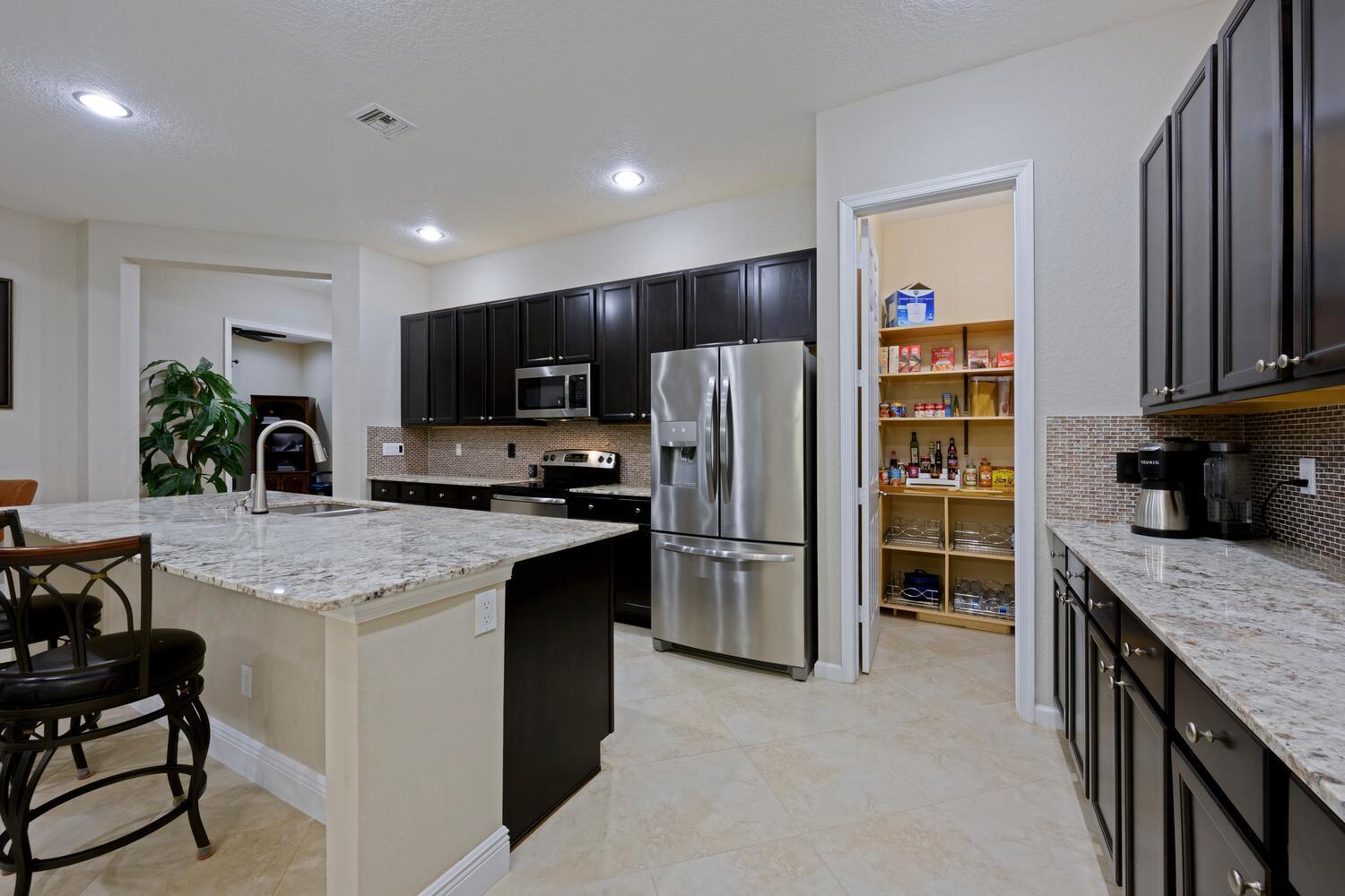 8024 Southwest Marin Drive Stuart, FL 34997 - Photo 6 of 26 a kitchen with stainless steel appliances granite countertop a refrigerator stove and oven