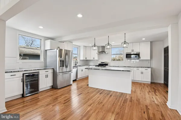 a large kitchen with stainless steel appliances granite countertop a stove a sink dishwasher a refrigerator and a wooden floor
