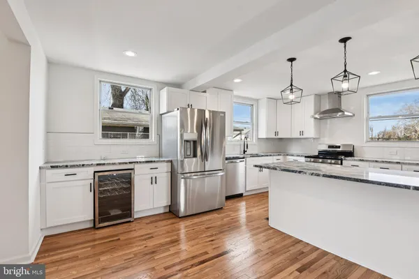 a kitchen with granite countertop kitchen island stainless steel appliances a sink cabinets and wooden floor