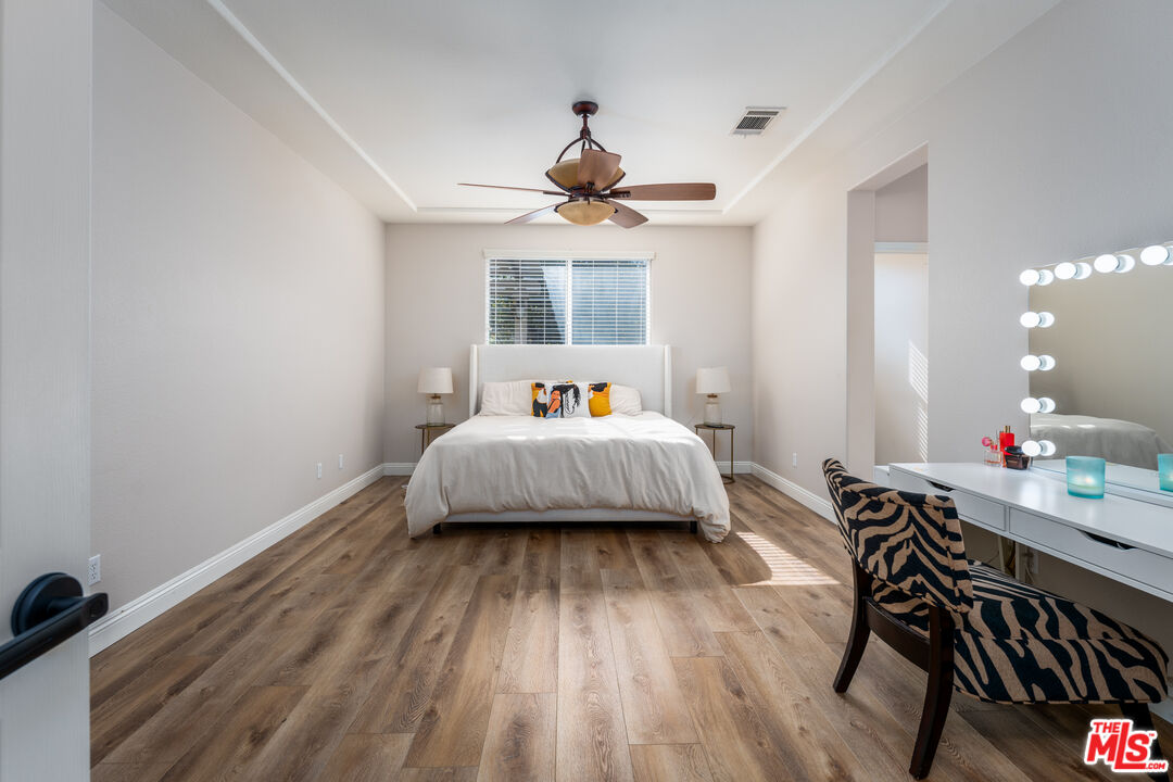14775 Prairie Smoke Road Eastvale, CA 92880 - Photo 14 of 36 a bedroom with a bed and wooden floor