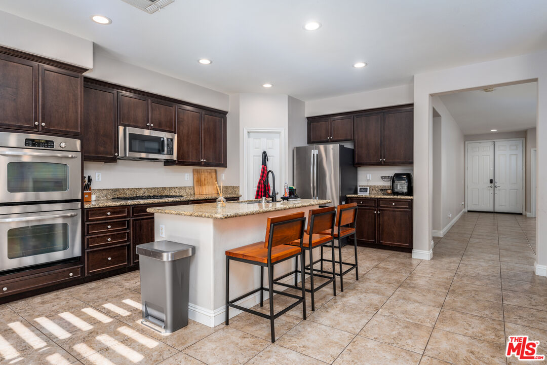 14775 Prairie Smoke Road Eastvale, CA 92880 - Photo 7 of 36 a kitchen with stainless steel appliances a stove a sink a microwave a refrigerator and cabinets