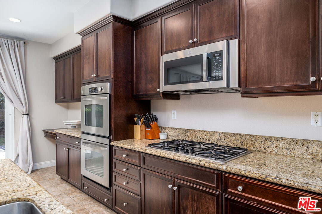14775 Prairie Smoke Road Eastvale, CA 92880 - Photo 8 of 36 a kitchen with stainless steel appliances granite countertop a stove microwave and refrigerator