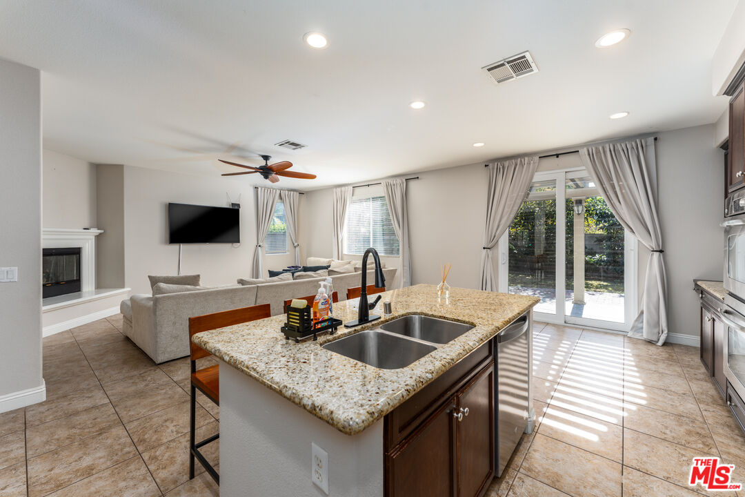 14775 Prairie Smoke Road Eastvale, CA 92880 - Photo 10 of 36 a kitchen with granite countertop a sink and a stove top oven with wooden floor