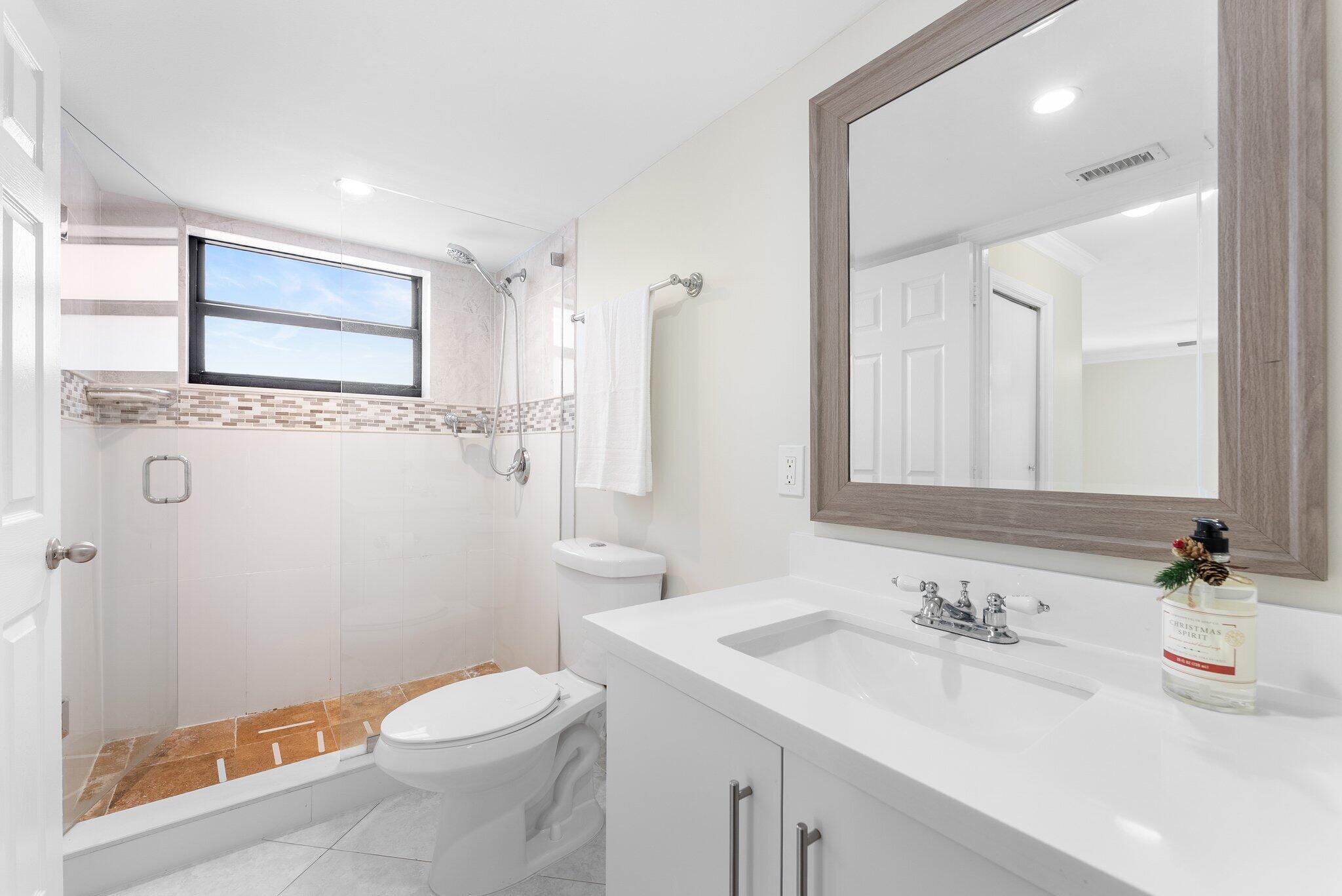 23490 Lyons Road, Unit 605 Boca Raton, FL 33428 - Photo 14 of 39 a bathroom with a sink a toilet a mirror and shower