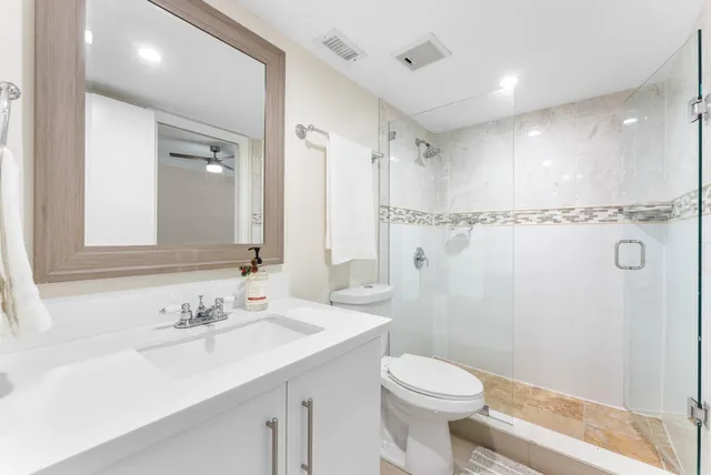 a bathroom with a sink a toilet a mirror and shower