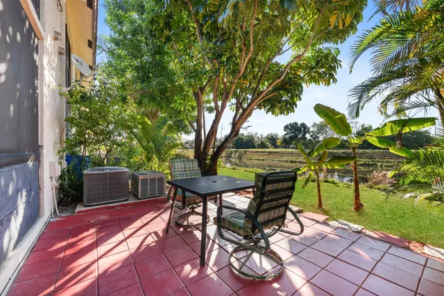 a view of a backyard with table and chairs and a barbeque with potted plants and large trees