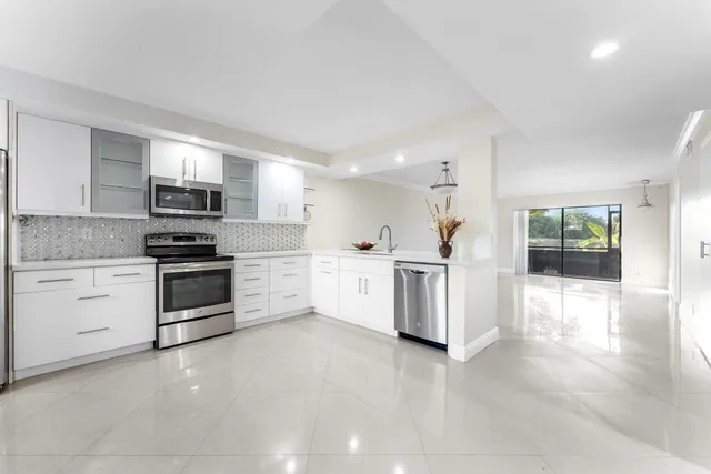 a kitchen with granite countertop white cabinets and stainless steel appliances