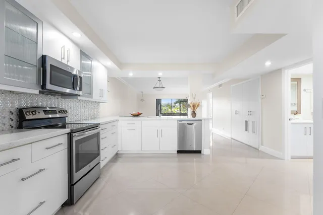 a large kitchen with white cabinets and stainless steel appliances
