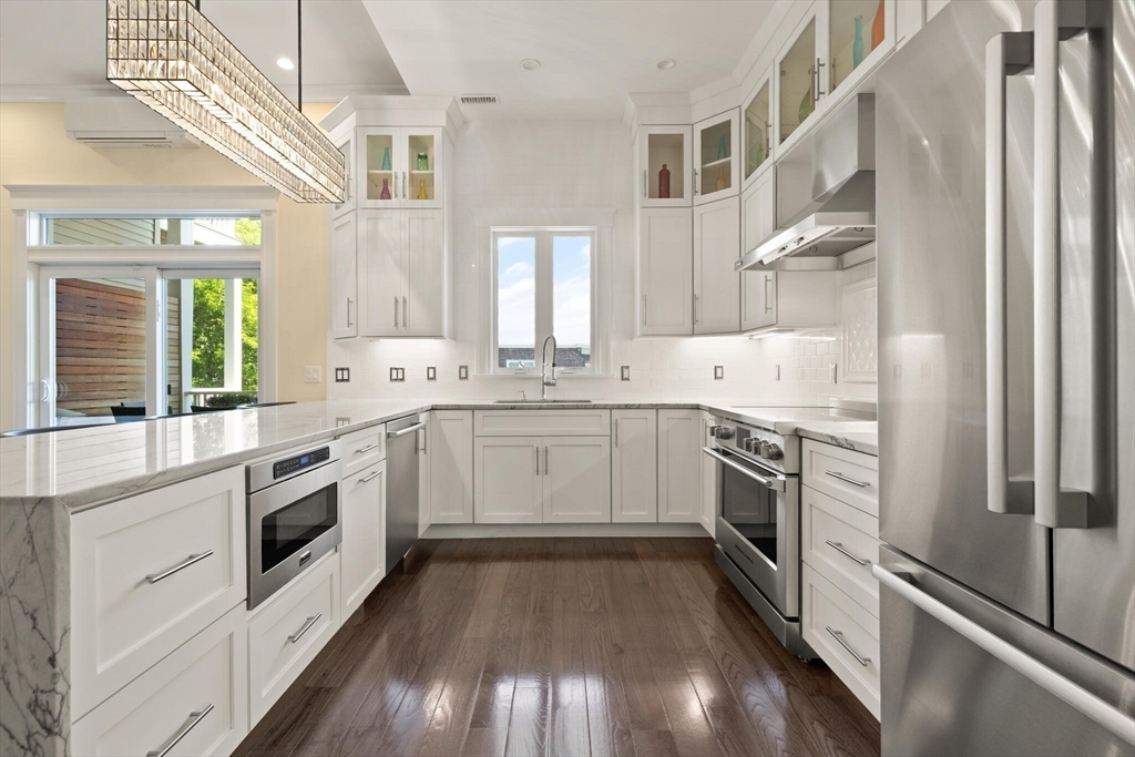 125 Heath Street Somerville, MA 02145 - Photo 15 of 42 a kitchen with a sink white cabinets stainless steel appliances and a window