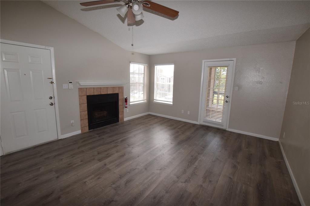 5533 Chrishire Way, Unit F201 Orlando, FL 32822 - Photo 6 of 12 an empty room with wooden floor fireplace and windows
