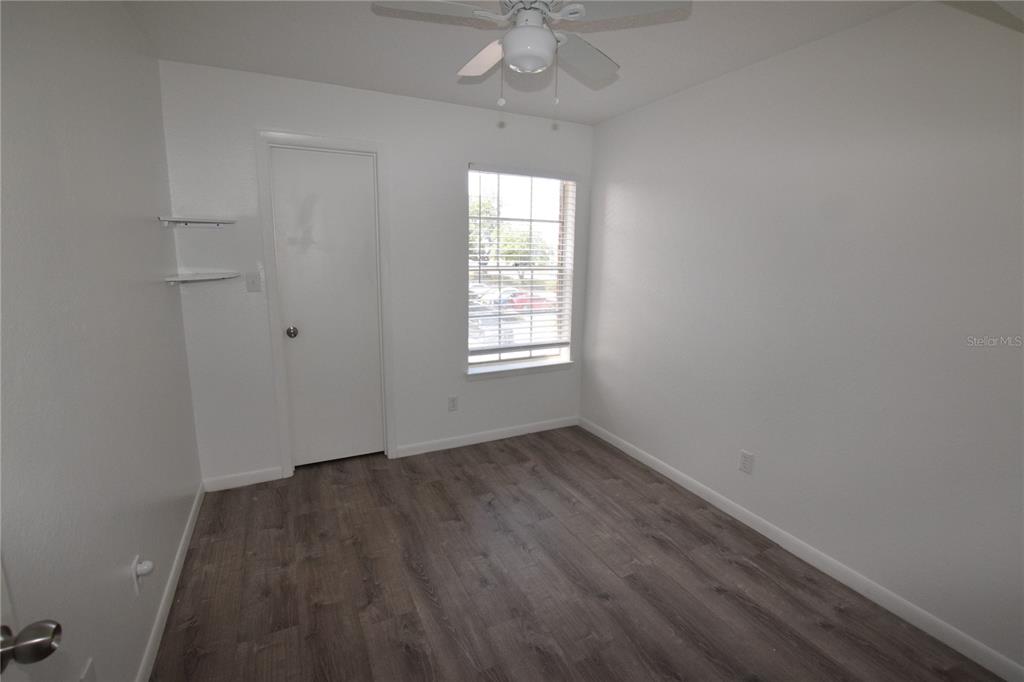 5533 Chrishire Way, Unit F201 Orlando, FL 32822 - Photo 9 of 12 an empty room with wooden floor chandelier fan and windows