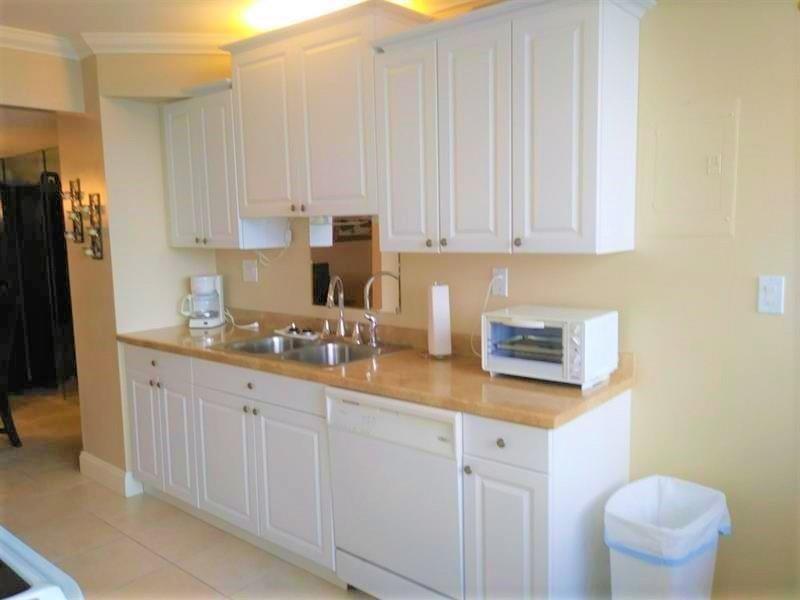 100 Golden Isles Drive, Unit 511 Hallandale Beach, FL 33009 - Photo 2 of 20 a kitchen with white cabinets and stainless steel appliances