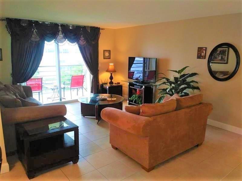 100 Golden Isles Drive, Unit 511 Hallandale Beach, FL 33009 - Photo 6 of 20 a living room with furniture a large window and a fireplace