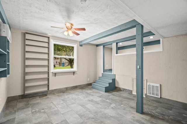 an empty room with windows and ceiling fan