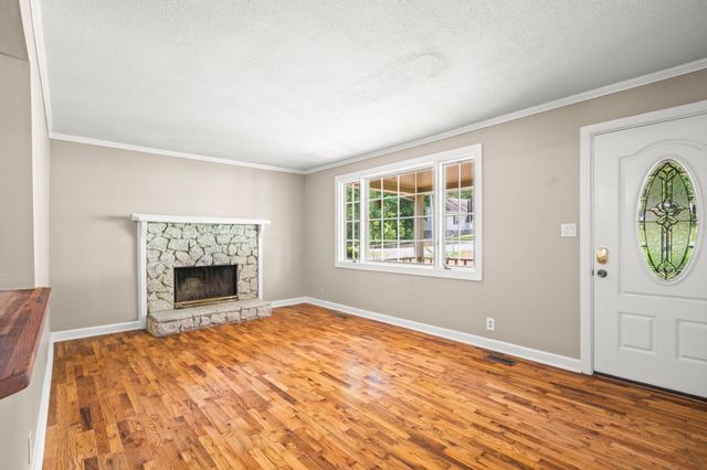 a view of an empty room with window and wooden floor