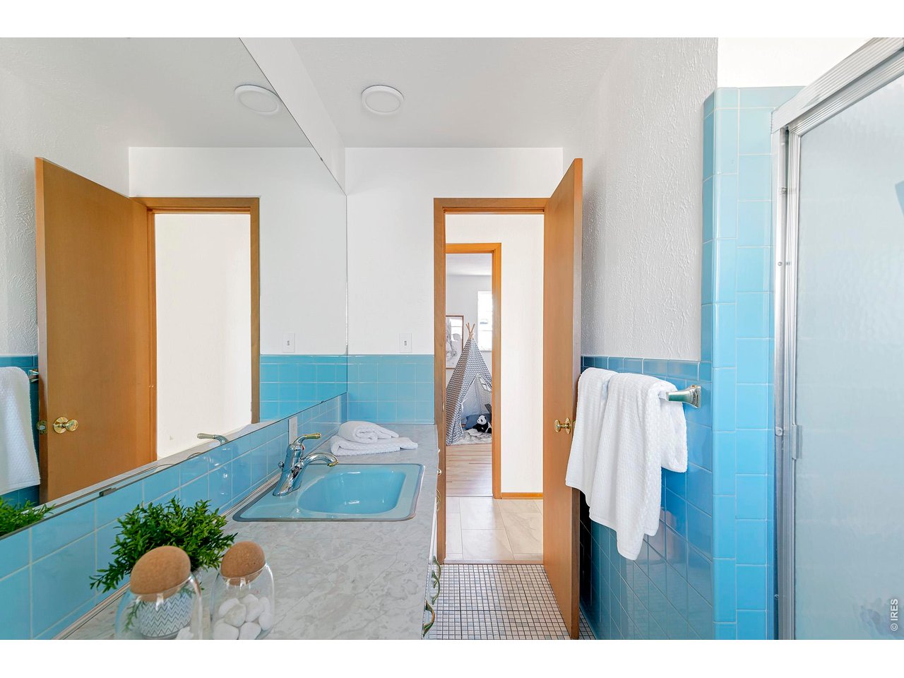2410 Grape Avenue Boulder, CO 80304 - Photo 29 of 50 A mid-century bath wrapped in classic sky-blue tile, complemented by a matching pastel sink for a true vintage look. Frosted glass shower doors, mosaic tile flooring, and a full wall mirror enhance the light