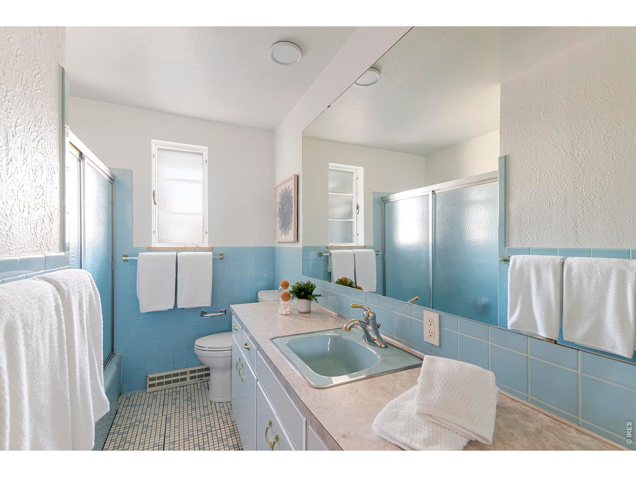 2410 Grape Avenue Boulder, CO 80304 - Photo 31 of 50 A delightful mid-century bath wrapped in classic sky-blue tile, complemented by a matching pastel sink for an authentic vintage look. Frosted glass shower doors, mosaic tile flooring, and a full wall mirror enhance the light