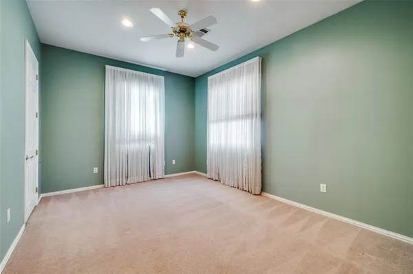 an empty room with chandelier fan and windows