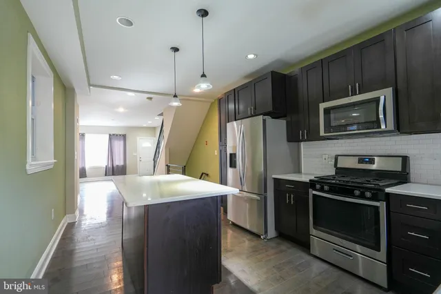 a kitchen with kitchen island a sink stainless steel appliances and cabinets