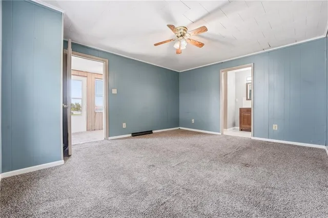 an empty room with chandelier fan and windows