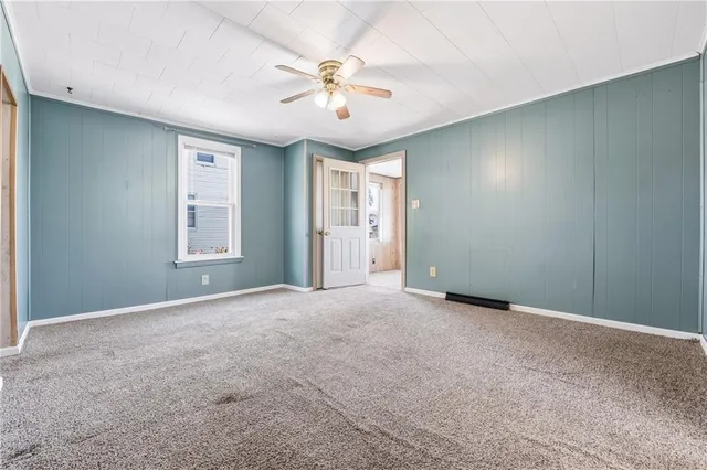 an empty room with windows and chandelier fan