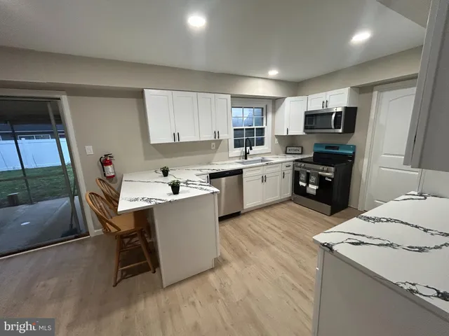 a kitchen with a sink a microwave a stove and white cabinets
