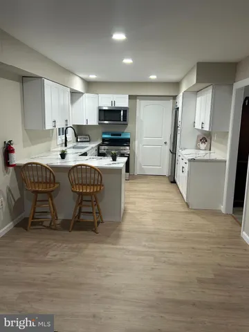 a kitchen with stainless steel appliances a sink a stove a refrigerator cabinets and chairs