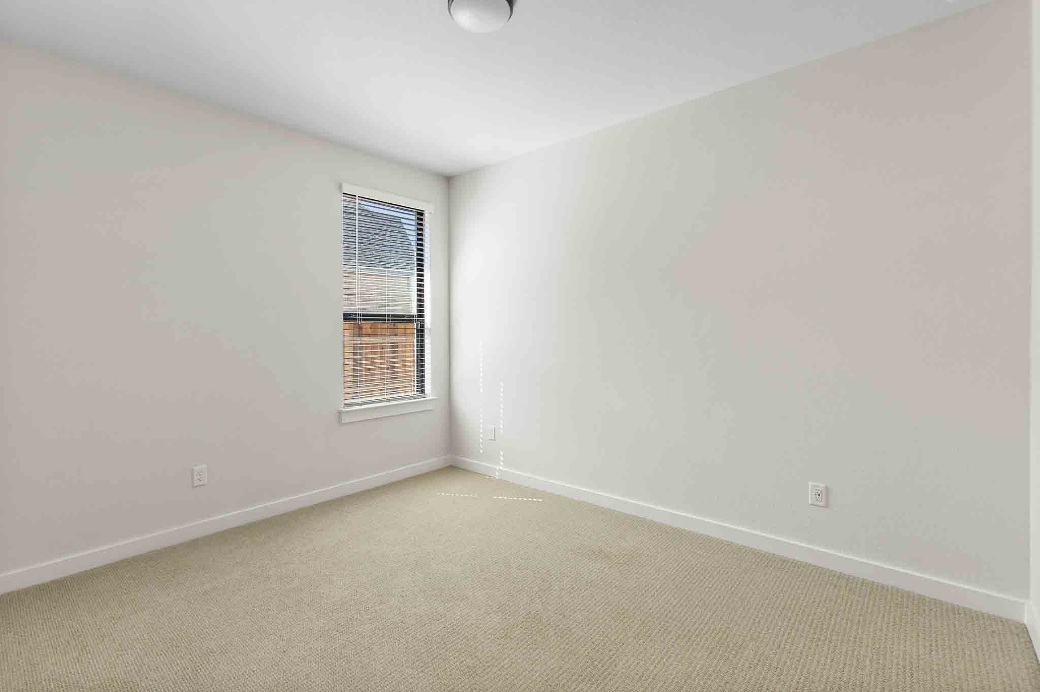 220 Basket Flower Loop Kyle, TX 78640 - Photo 28 of 40 A well-lit bedroom features plush carpeting and a window with blinds, offering comfort and privacy.
