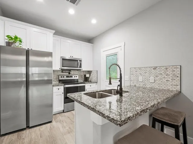 a kitchen with stainless steel appliances granite countertop a sink refrigerator and microwave