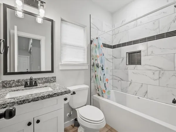 a bathroom with a granite countertop sink a toilet and shower