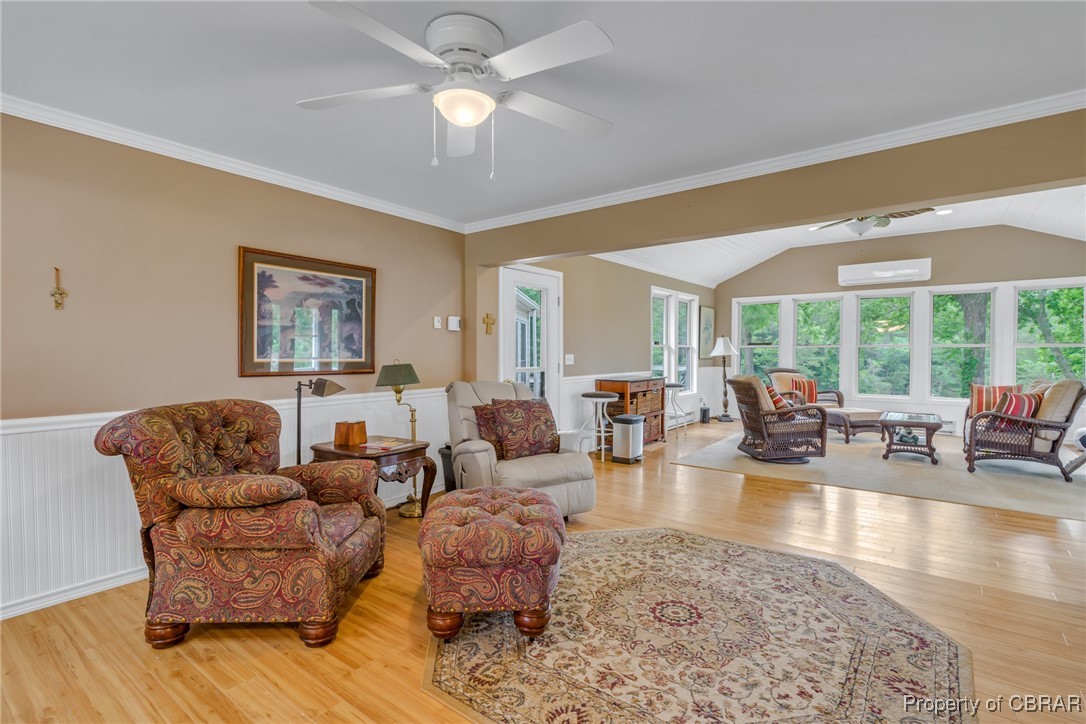 86 Greenfield Road Lancaster, VA 22503 - Photo 26 of 44 Living area with wood finished floors, a wainscoted wall, a wall unit AC, vaulted ceiling, and ceiling fan
