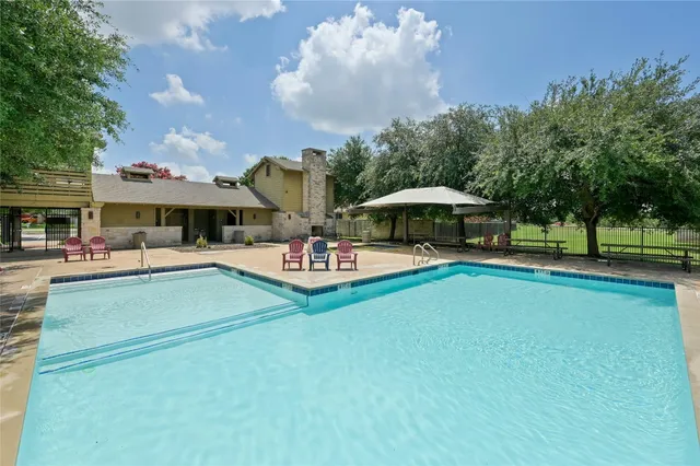 a view of swimming pool with outdoor seating and trees in the background
