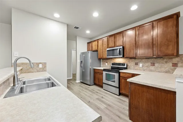 a kitchen with granite countertop wooden cabinets stainless steel appliances and a sink