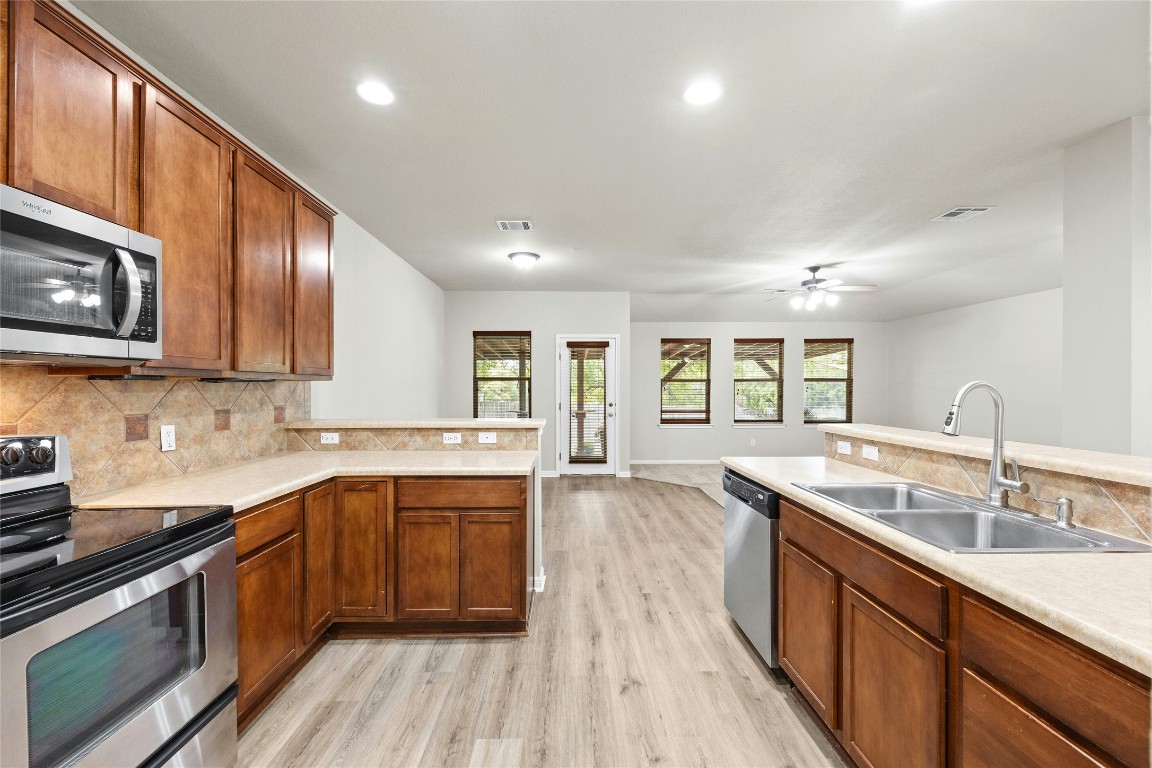 7614 Buck Meadow Drive Georgetown, TX 78628 - Photo 6 of 30 a kitchen with stainless steel appliances granite countertop wooden cabinets sink stove and microwave