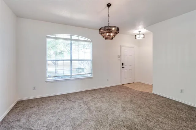 an empty room with a chandelier fan and windows