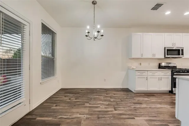 a view of a kitchen with a sink dishwasher a stove top oven a refrigerator with white cabinets and wooden floor