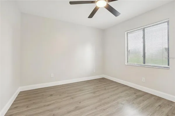a view of an empty room with wooden floor and a window