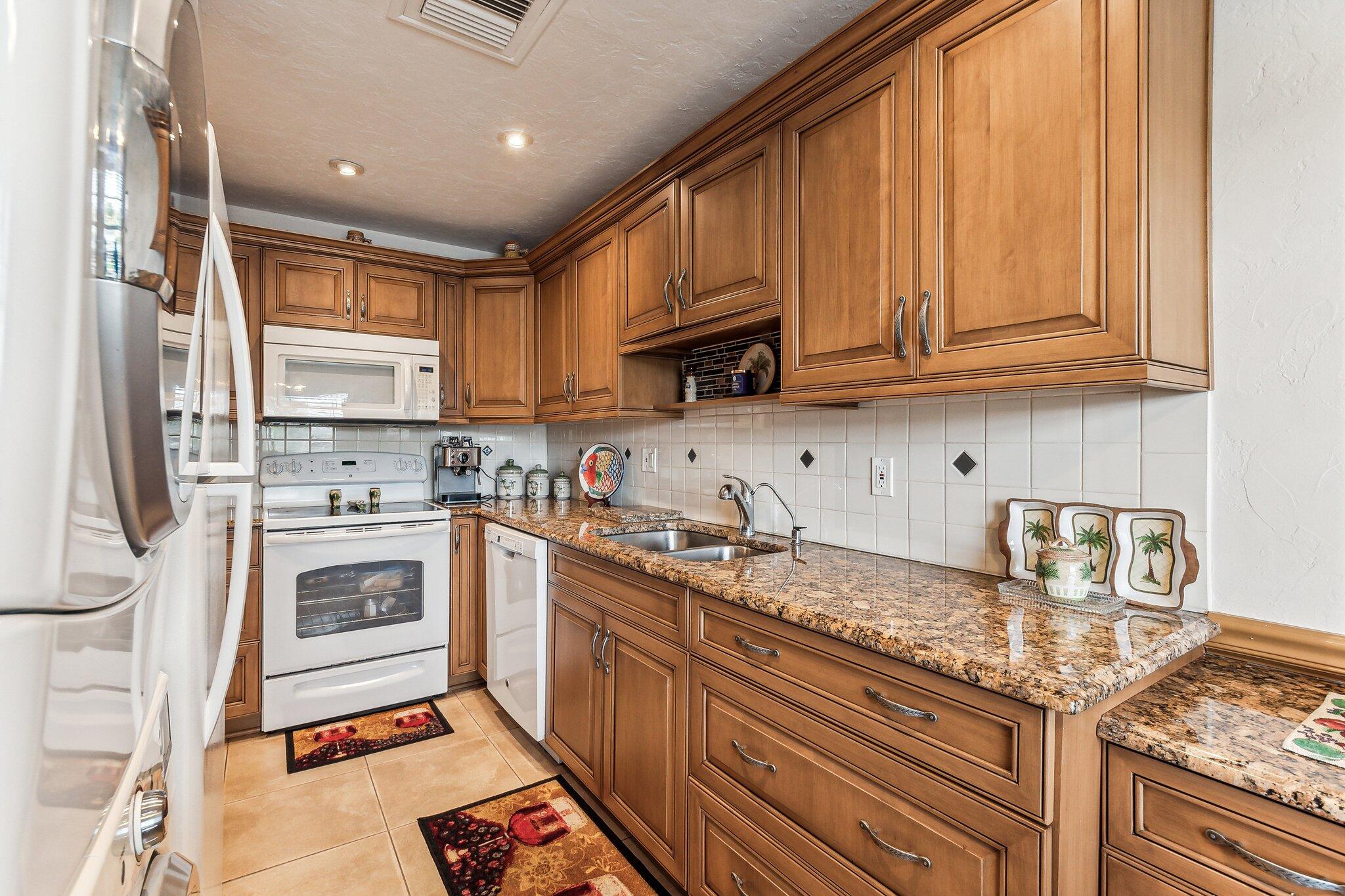 a kitchen with granite countertop stainless steel appliances a stove sink and cabinets