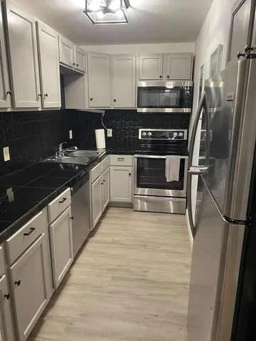 a kitchen with granite countertop a refrigerator and a stove top oven