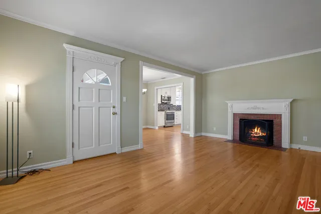an empty room with wooden floor fireplace and windows