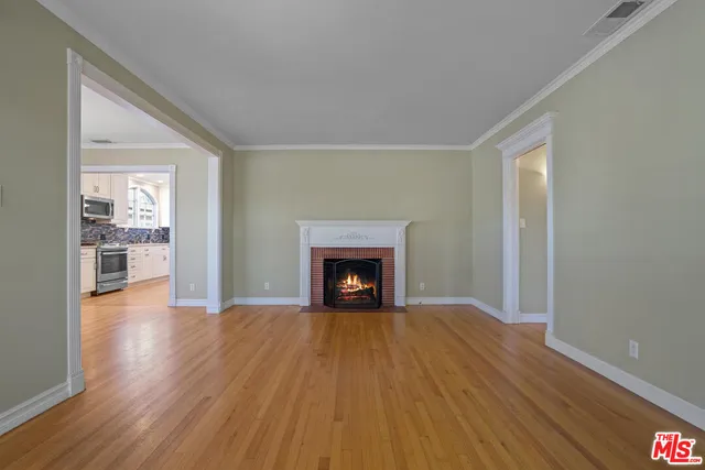 a view of an empty room with wooden floor fireplace and a window