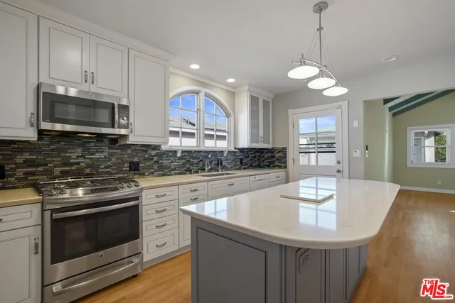 a kitchen with stainless steel appliances kitchen island granite countertop a stove a sink a microwave and wooden cabinets