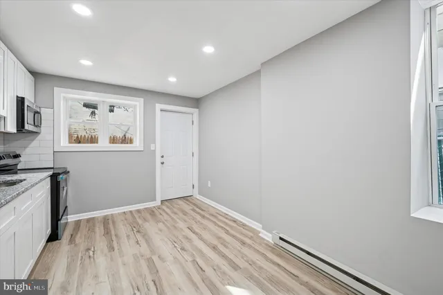 a view of hallway with window and wooden floor