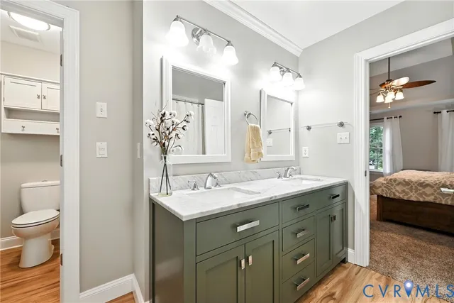 a en suite bathroom with a granite countertop double vanity sink a mirror and a toilet