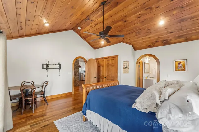 a spacious bedroom with a bed a dresser and wooden floor