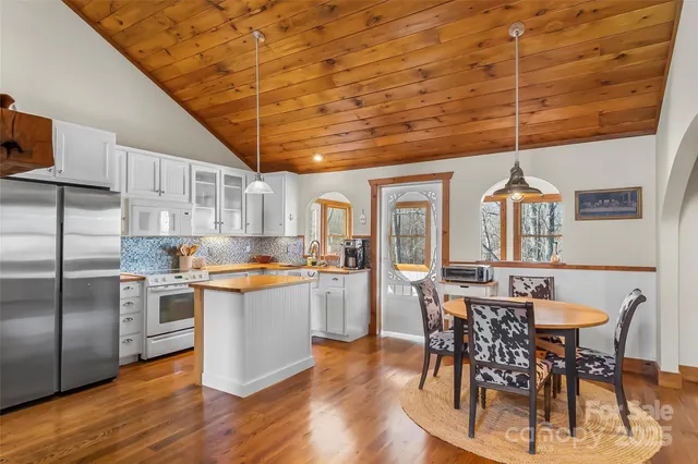 a kitchen with stainless steel appliances granite countertop a table chairs stove and refrigerator