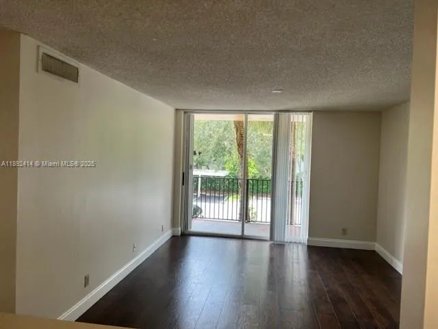a view of a big room with wooden floor and windows
